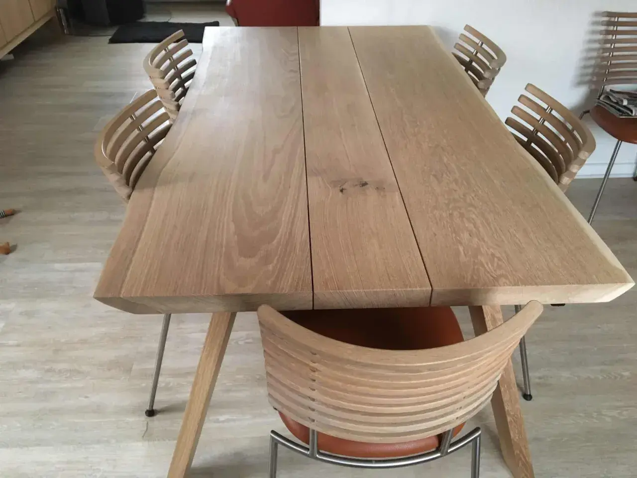 Ett modernt ekbord med en naturlig, pigmenterad oljeyta, omgivet av stilrena stolar med träribbor och lädersits.