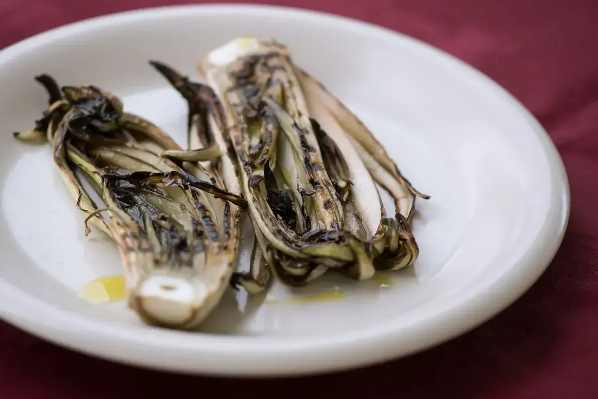 Radicchio grigliato in friggitrice ad aria, servito su un piatto bianco con un filo d'olio.