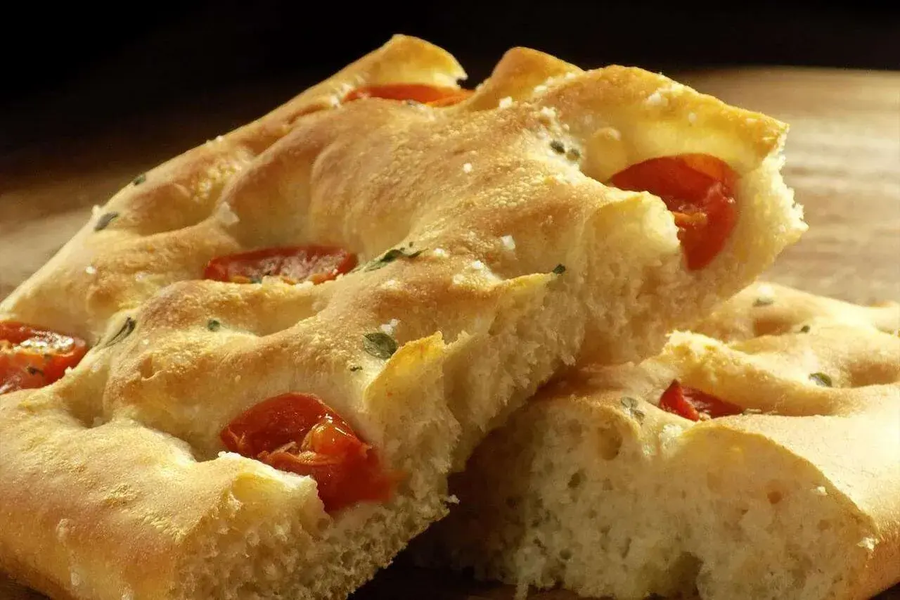 Focaccia moelleuse aux tomates et herbes, un délice qui rappelle la pizza.