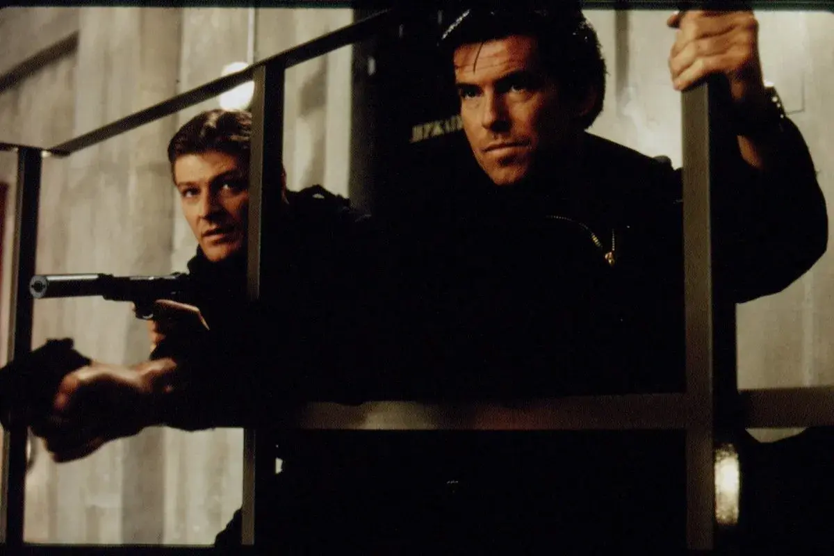 Pierce Brosnan och en kollega i actionfyllda filmer. De är redo för strid med vapen i hand.