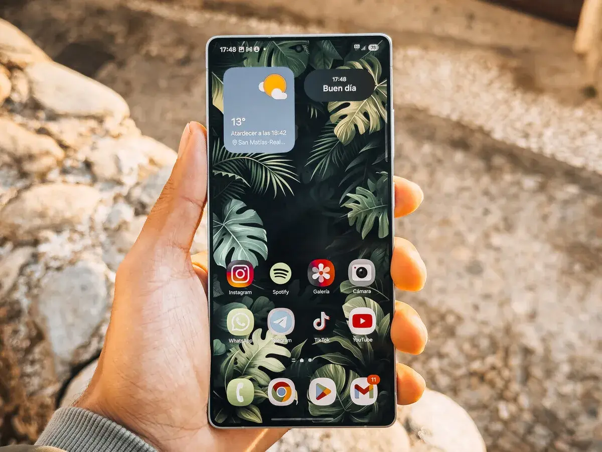 Mano sujetando un teléfono Android con iconos de aplicaciones personalizables, mostrando cómo cambiar tamaño iconos android para una mejor visualización.