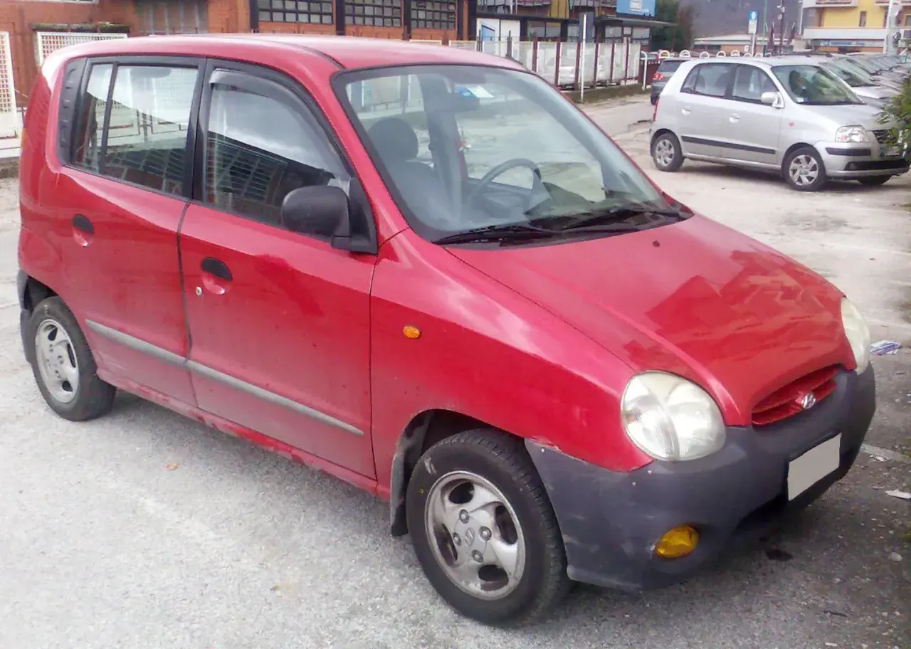 Röd Hyundai Atos parkerad utomhus. En annan silverfärgad bil syns i bakgrunden.