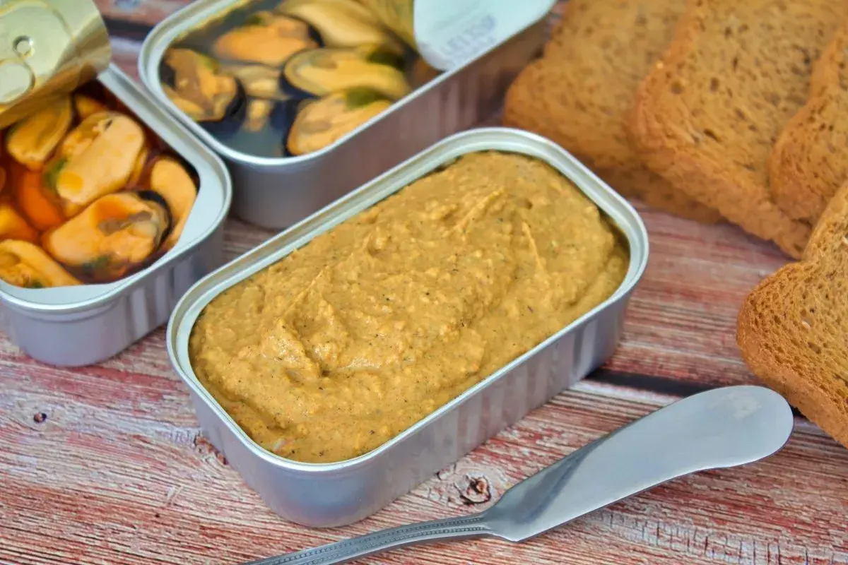Pate de mejillones en lata, junto a mejillones en escabeche y tostadas.