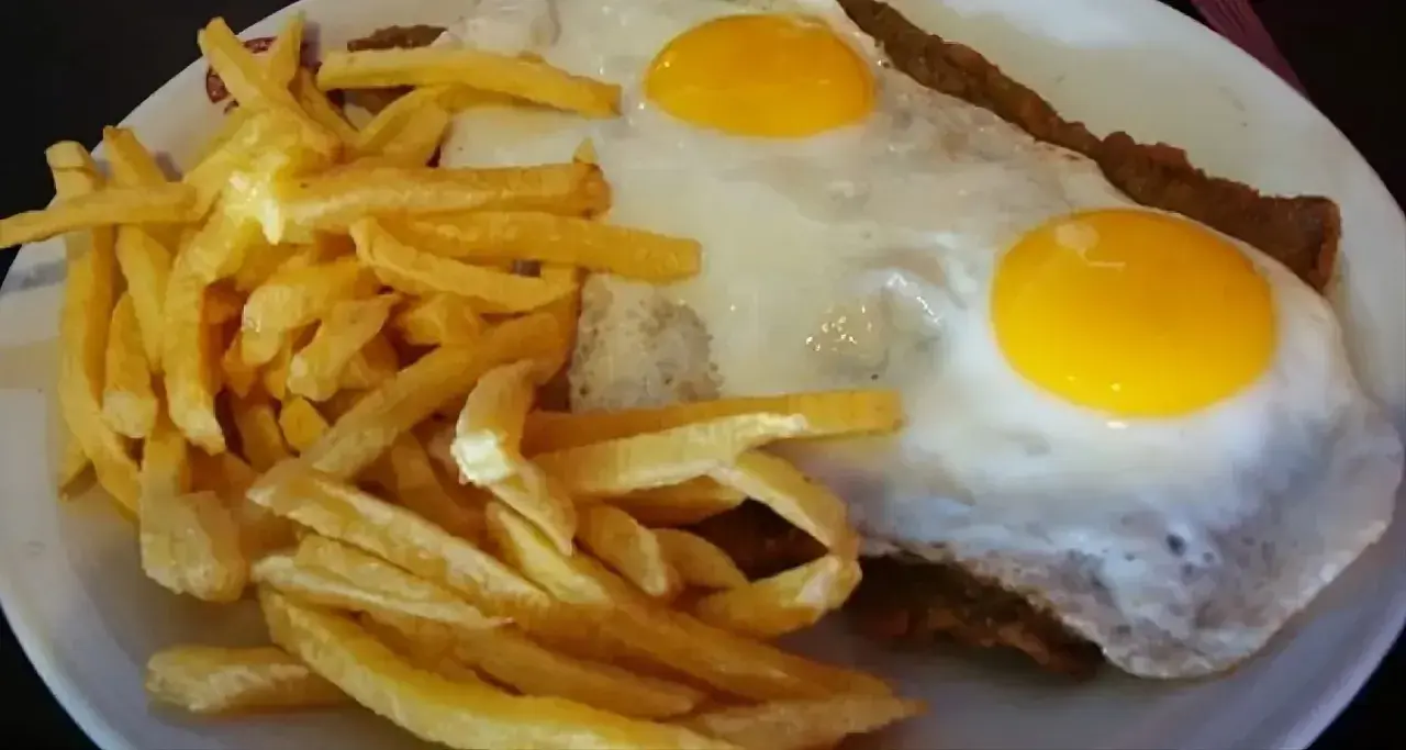 Un delicioso plato de milanesa a caballo, con dos huevos fritos y papas fritas crujientes.