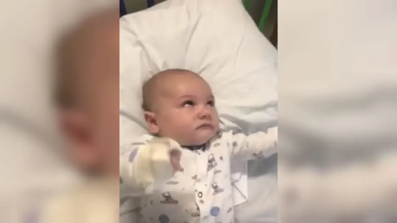 Bebé en pijama con patrones de nubes y lunas, con la mirada perdida, podría estar experimentando espasmos infantiles.
