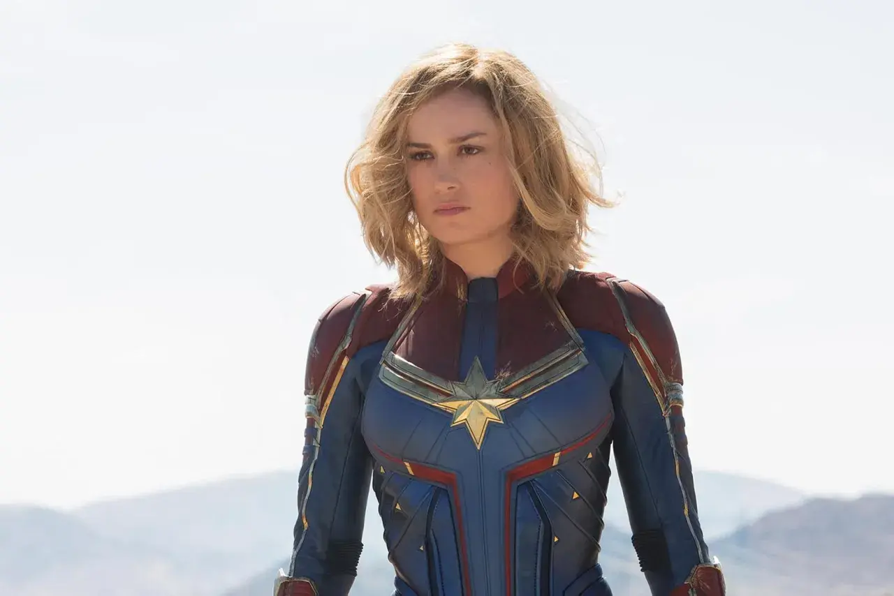 Captain Marvel, en armure bleue et rouge, prête à défendre la Terre. Elle est la réponse à qui est Captain Marvel.