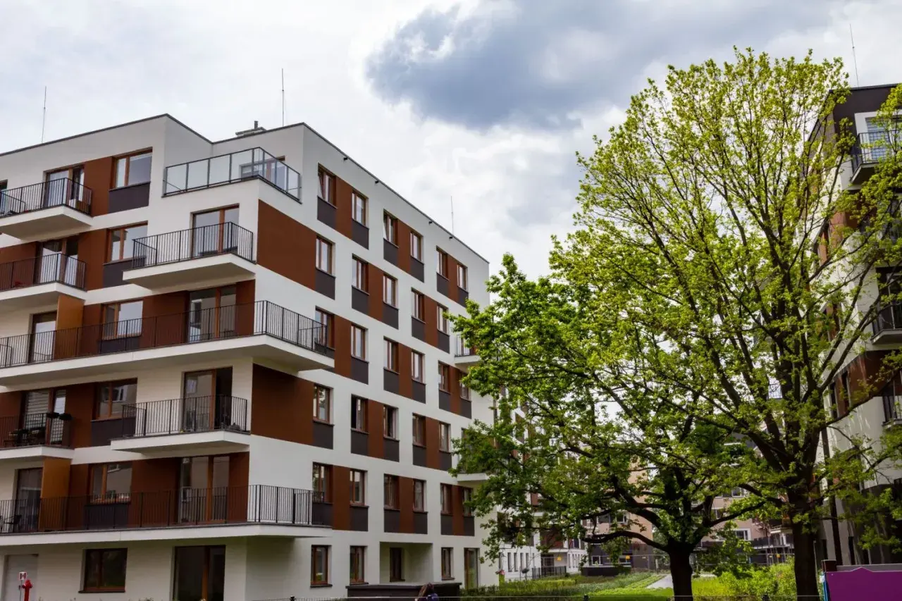 Nowoczesne bloki mieszkalne w stylu riviera park, z balkonami i zielenią.