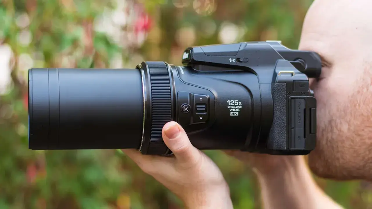 Un uomo usa una fotocamera bridge con zoom 125x. Scopri cosa sono le fotocamere bridge e la loro versatilità.