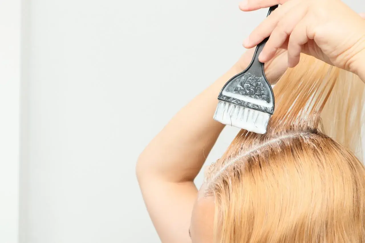 Persona se aplica tinta en el cabello, un proceso de tinta en casa para un cambio de look.