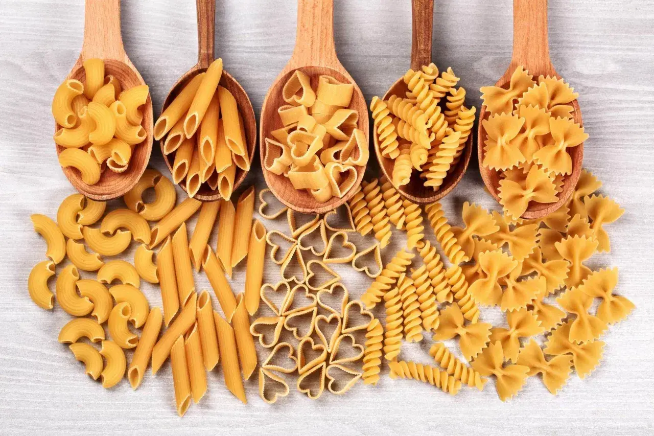 Różnorodne kształty makaronu, od penne po serduszka i kokardki, prezentują bogactwo produkcji makaronu.