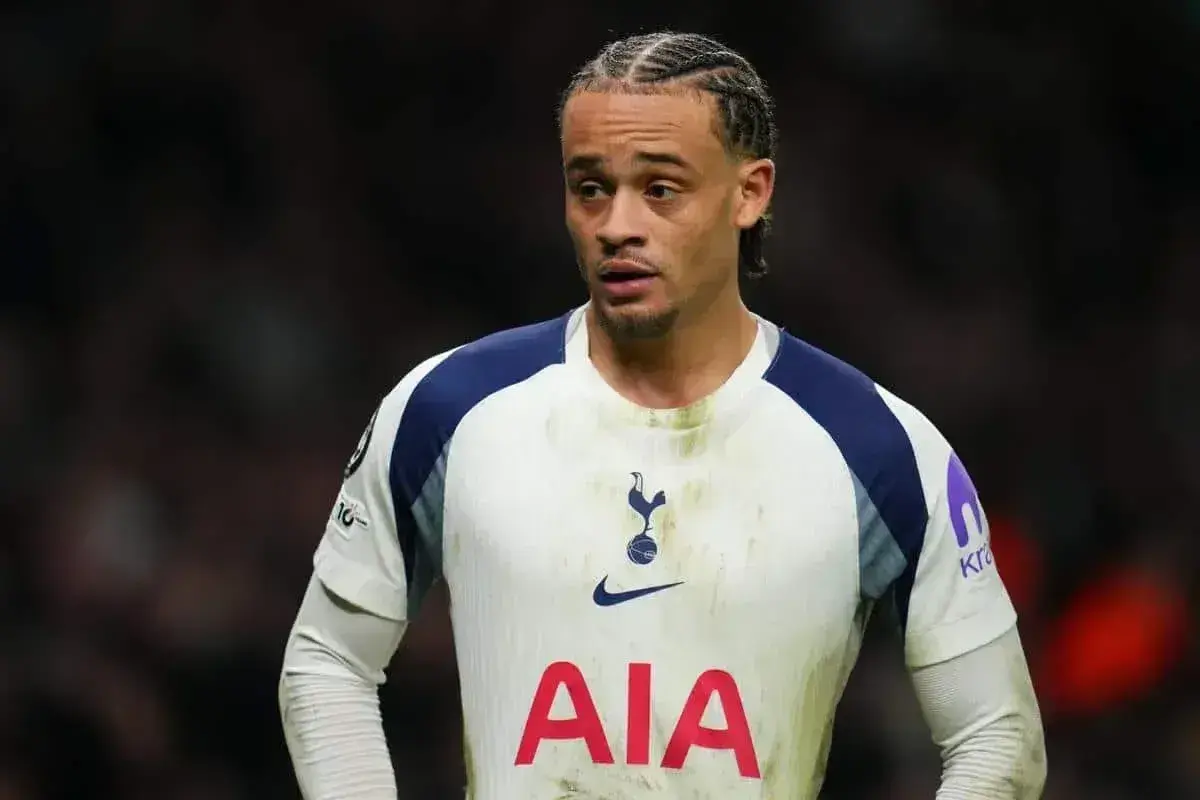 Jeden z tottenham zawodnicy w białej koszulce z granatowymi rękawami, z charakterystyczną fryzurą i skupionym wyrazem twarzy.
