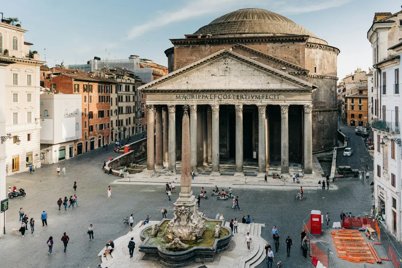 La Piazza della Rotonda à Rome, avec le majestueux Panthéon et sa fontaine. Des passants profitent de la journée ensoleillée.