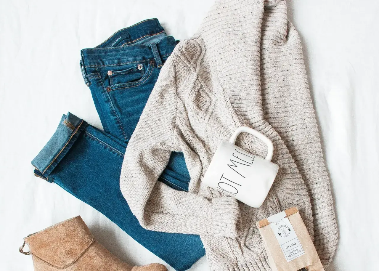 Un jean, un pull torsadé, une tasse et une botte en daim : un parfait style vestimentaire hiver pour une journée cosy.