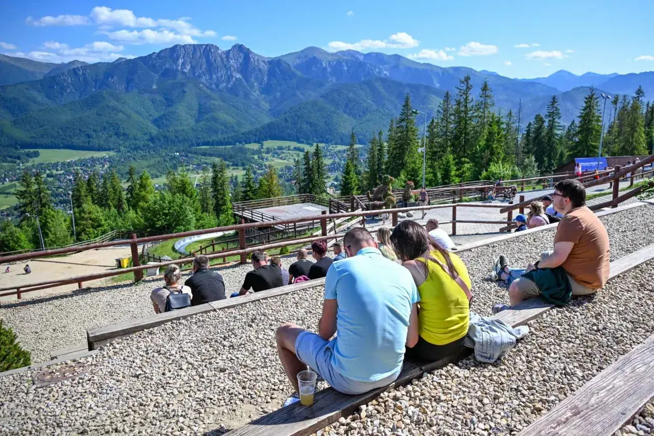 Widok na Tatry z widowni, gdzie ludzie odpoczywają, ciesząc się atrakcjami Poronina.