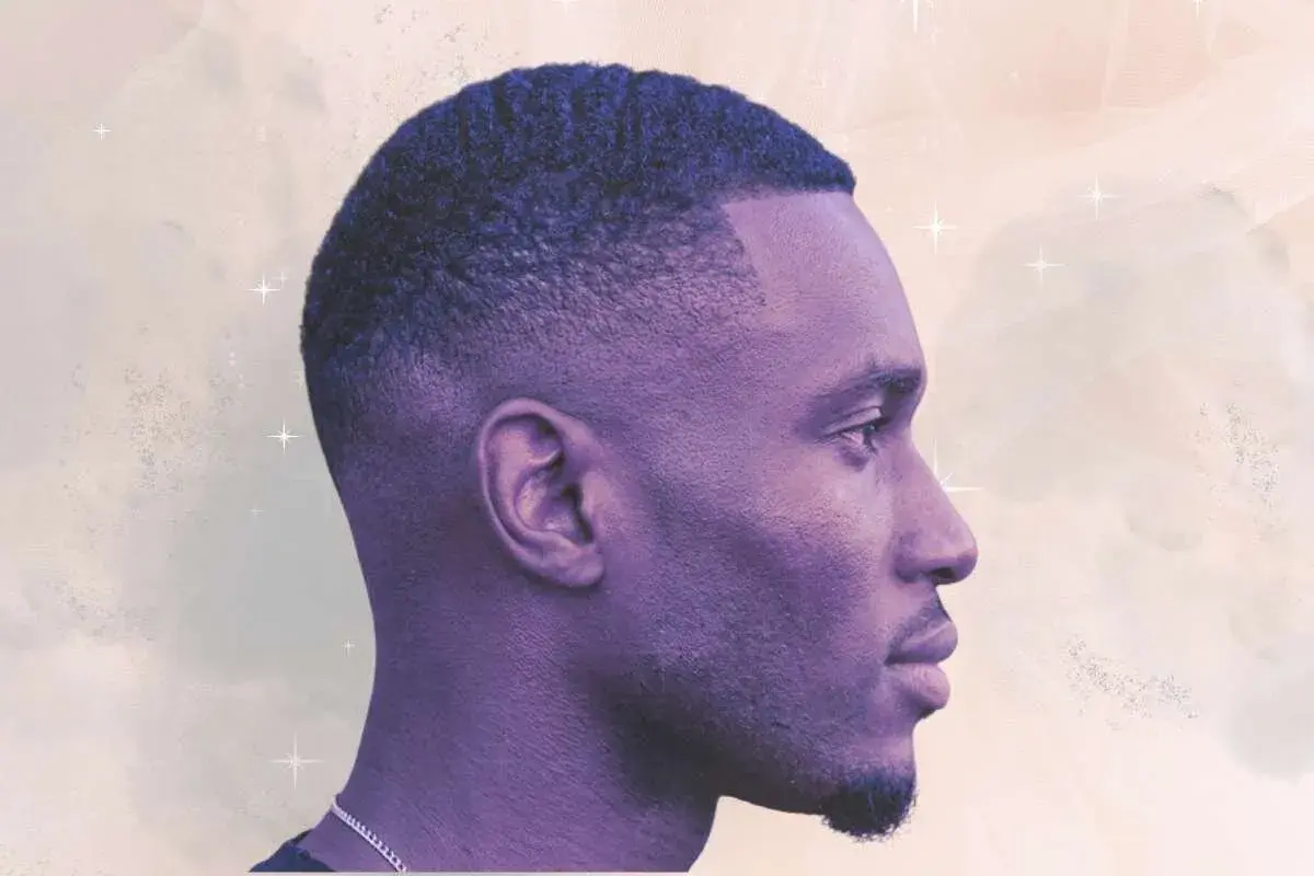 Perfil de hombre con un corte de pelo tuper fade, ondas definidas y barba corta.