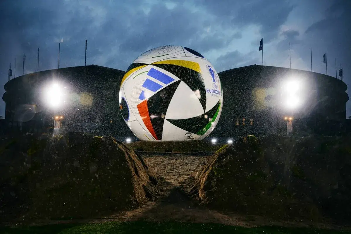 Gigantyczna piłka mistrzostw europy, symbol nadchodzącego turnieju, lśni w deszczu przed stadionem.