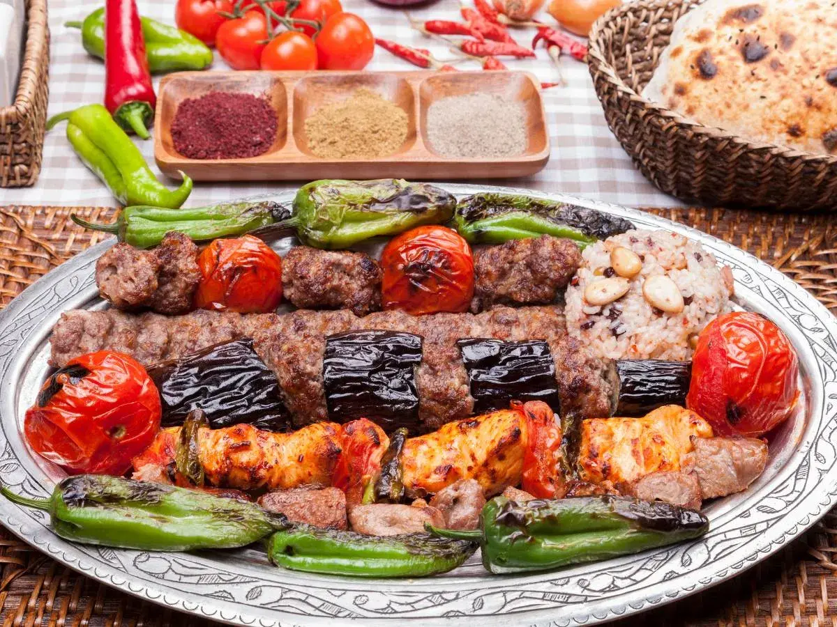 Turecka potrawa: grillowane mięso, bakłażany, pomidory i papryka na talerzu, obok ryż i pieczywo.