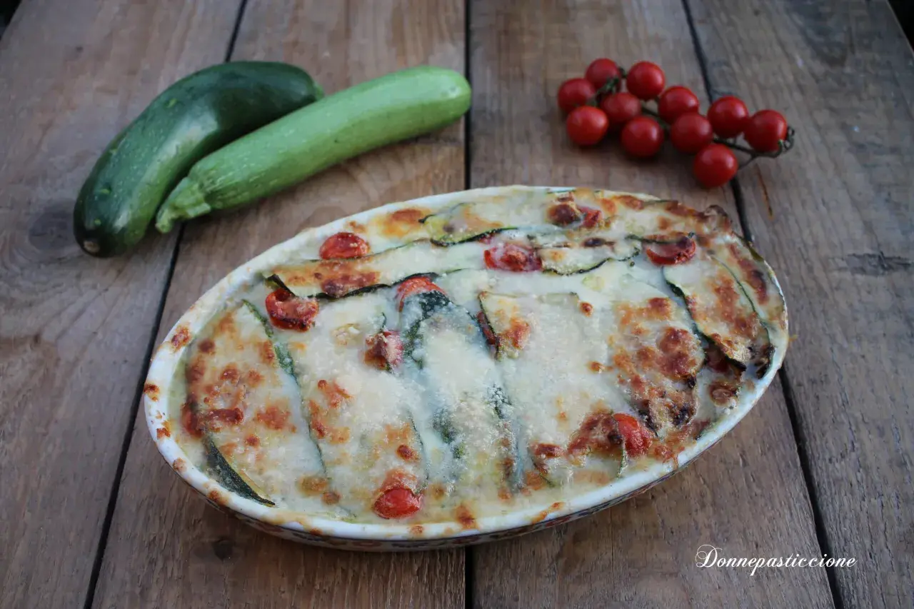Parmigiana di zucchine non fritte, con pomodorini e formaggio filante, pronta per essere gustata.