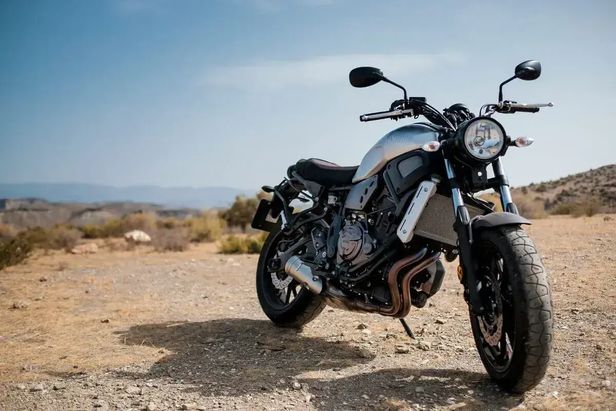 Motocykl stojący na pustynnym, kamienistym podłożu pod błękitnym niebem.