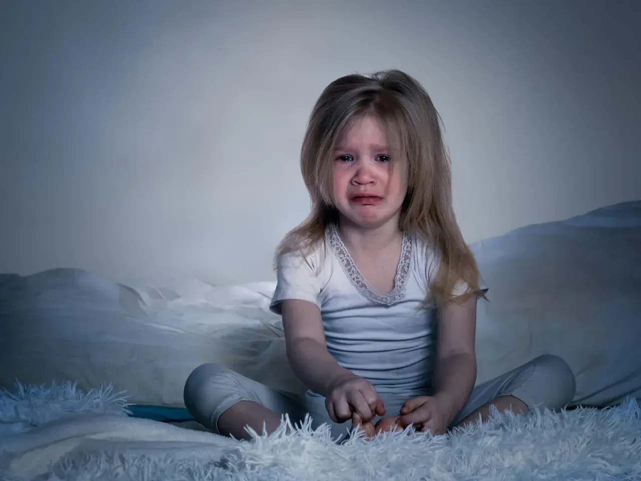 Verängstigtes Kind weint im Bett. Ein kleiner Junge hat einen Nachtschreck. Was tun?