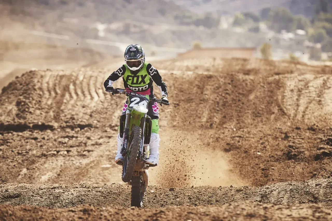 Motocrossowy zawodnik w stroju z logo Fox, jak prawdziwy fox titan, pędzi po piaszczystym torze, wzbijając tumany kurzu.