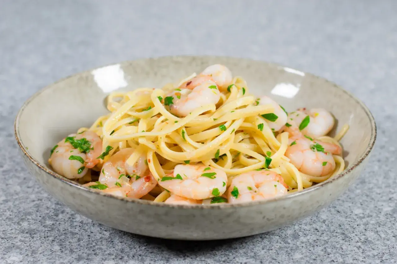 En skål med linguine och scampi, perfekt för ett snabbt scampi recept. Garnerad med färsk persilja.