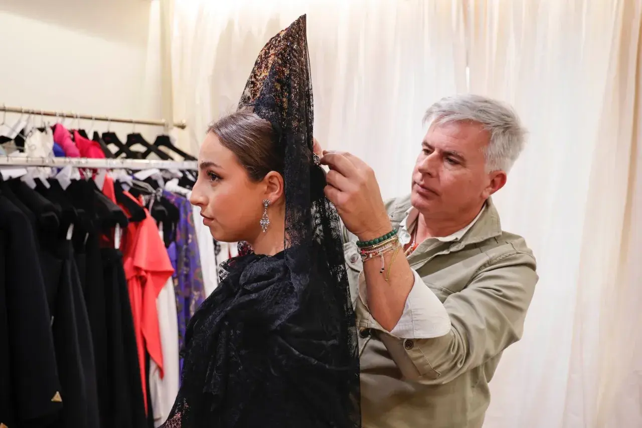 Hombre ayuda a mujer a cómo hacer moño para mantilla, ajustando el velo negro con encaje.