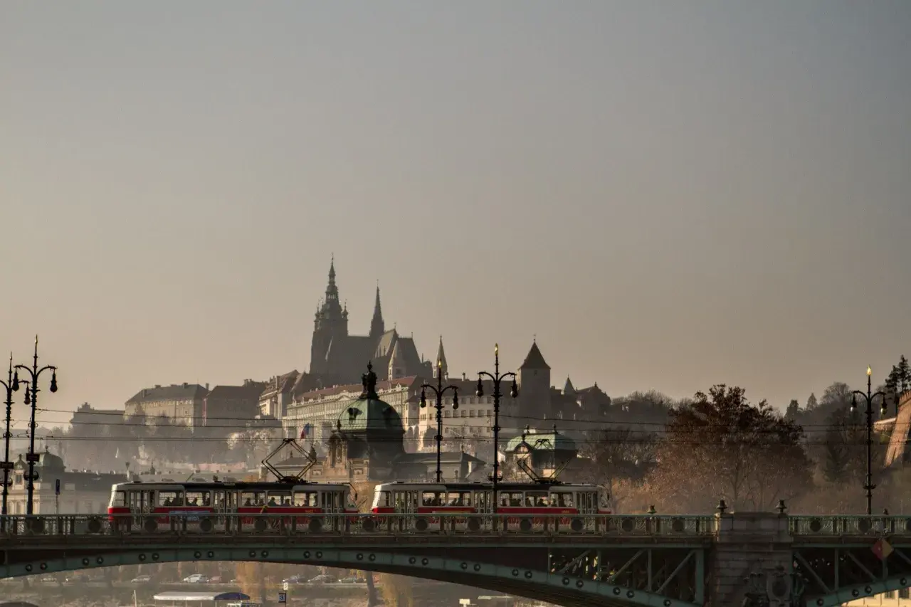 Most w Czechach z tramwajami na tle zamku.