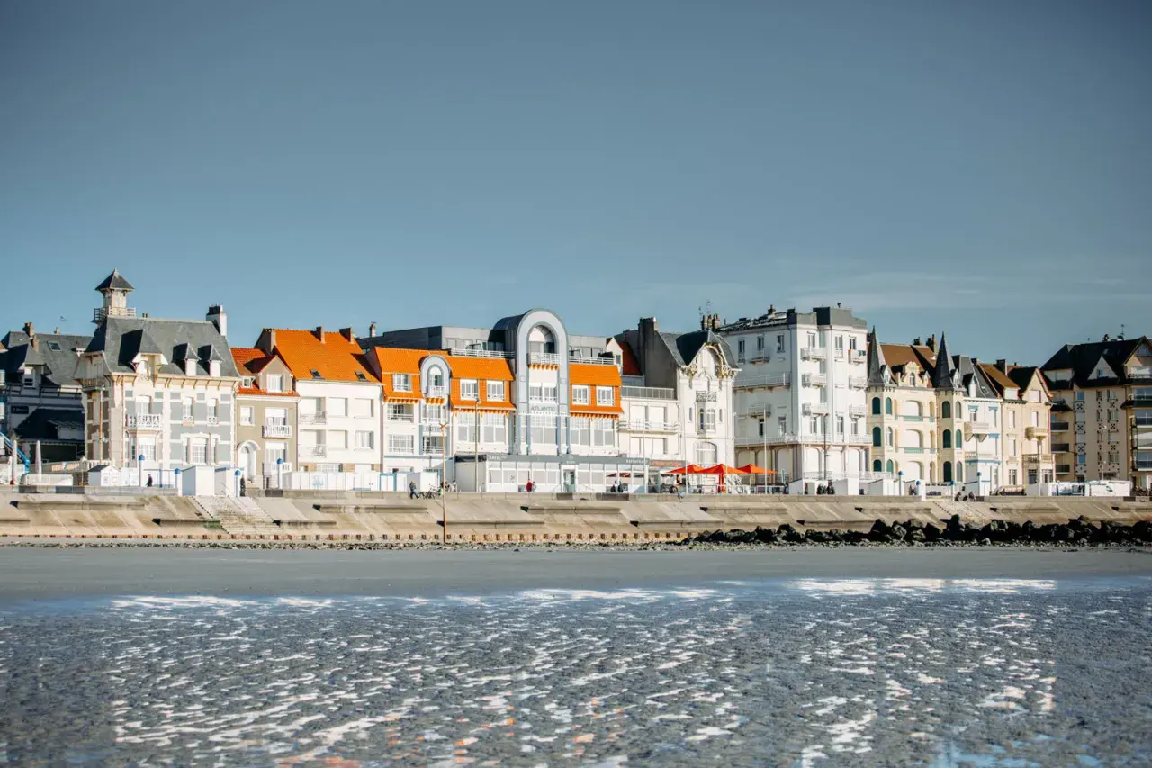 Bâtiments colorés bordant la plage sur la Côte d'Opale, avec des toits orange vif et des façades blanches et grises.