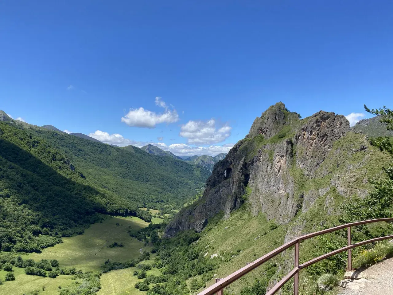 Un valle verde y montañoso con un arco natural en la roca, ideal para rutas circulares en Somiedo.