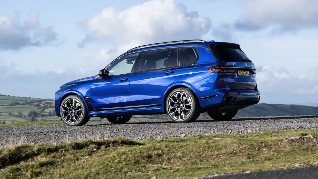 Błękitne BMW X7 M60i na tle malowniczego krajobrazu.
