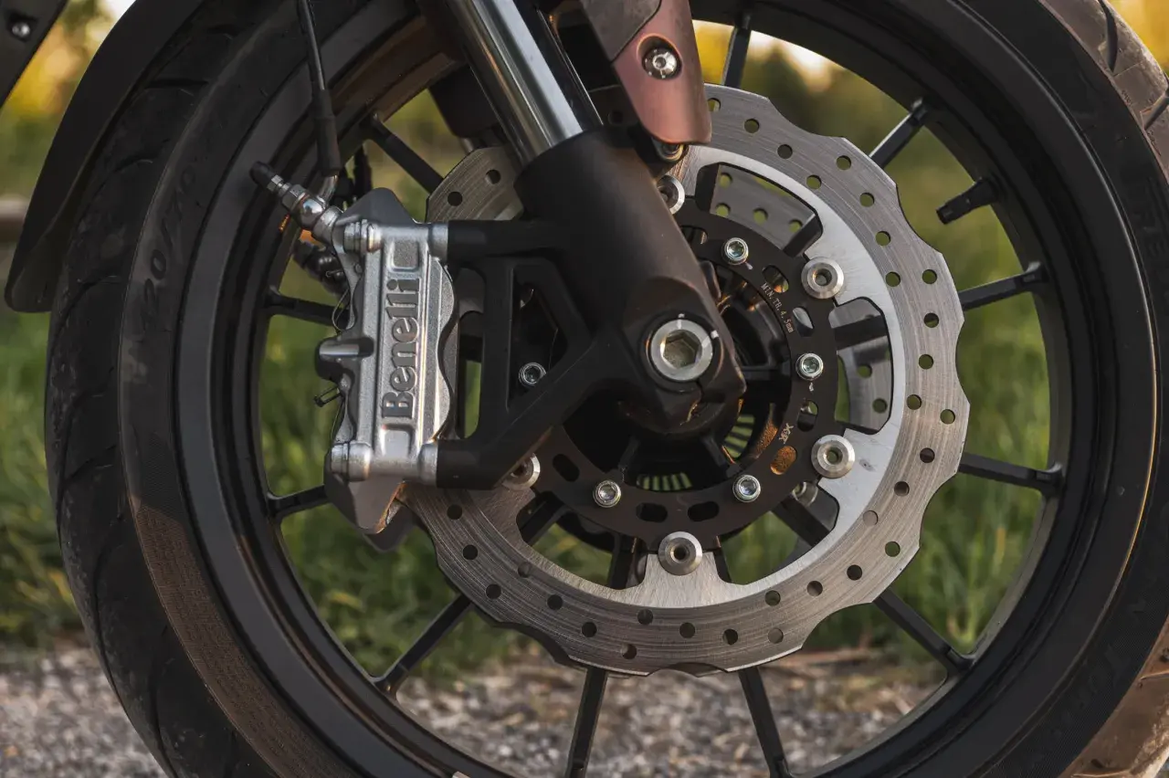 Zbliżenie na tarczę hamulcową motocykla z zaciskiem Benelli.