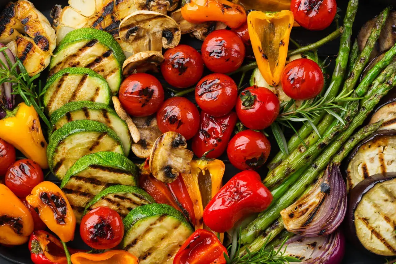Un assortiment coloré de légumes grillés, parfait en accompagnement barbecue : courgettes, tomates cerises, poivrons, asperges, champignons, aubergines et oignons rouges.
