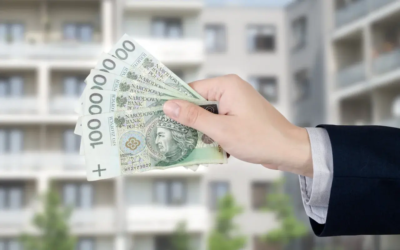 Dłoń trzyma banknoty 100 zł. Zastanawiasz się, ile wynosi dodatek mieszkaniowy?