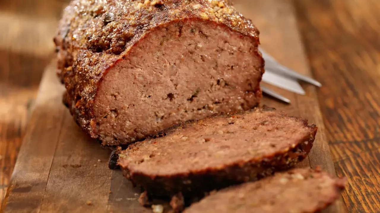 Un delizioso polpettone al forno, tagliato a fette su un tagliere di legno, pronto per essere gustato.
