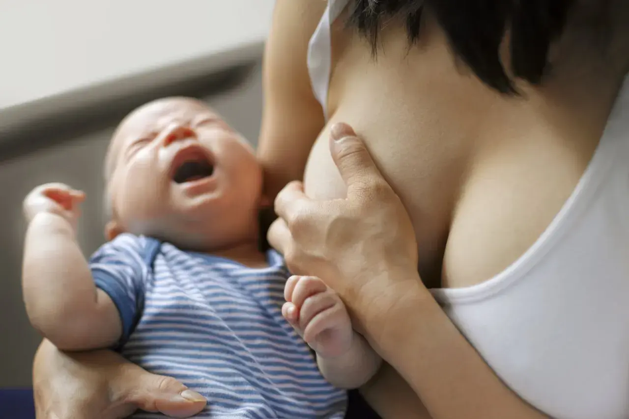 Bébé pleure pendant l'allaitement, possible signe de mastite infectieuse.