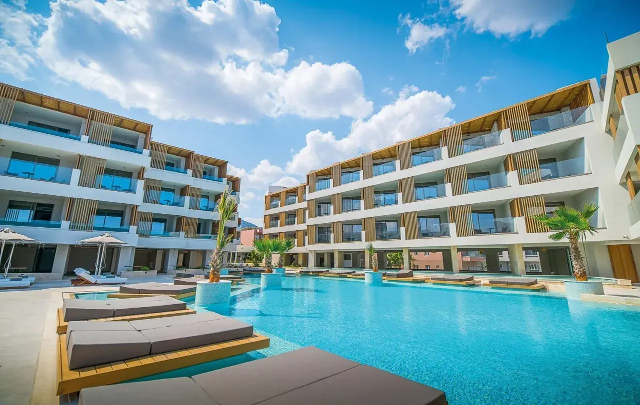 Entspannter Urlaub im Akasha Beach Hotel & Spa: Moderne Architektur, ein einladender Pool und Liegen unter blauem Himmel.