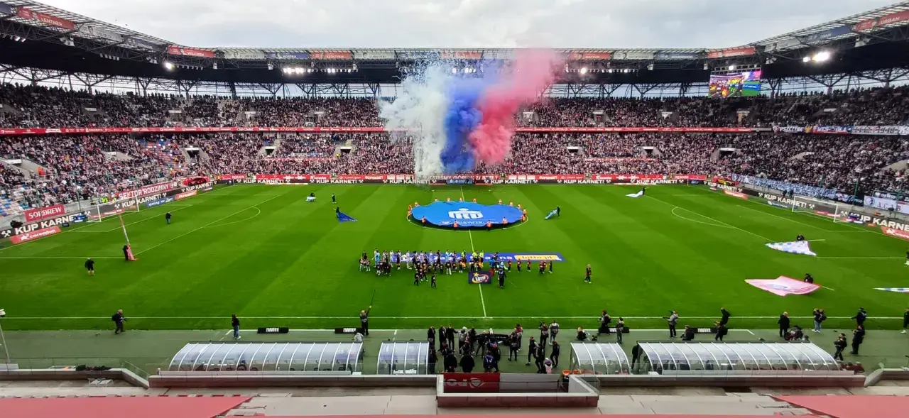 Oprawa meczu Górnik Zabrze – Cracovia: dym w barwach klubowych, zawodnicy na murawie i pełne trybuny.