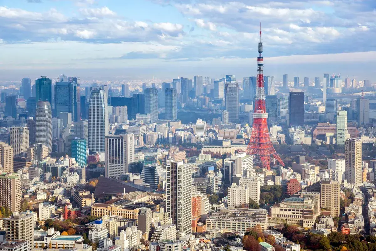 Rozległy krajobraz tokio miasto z wieżą Tokyo Tower na pierwszym planie i licznymi drapaczami chmur w tle.