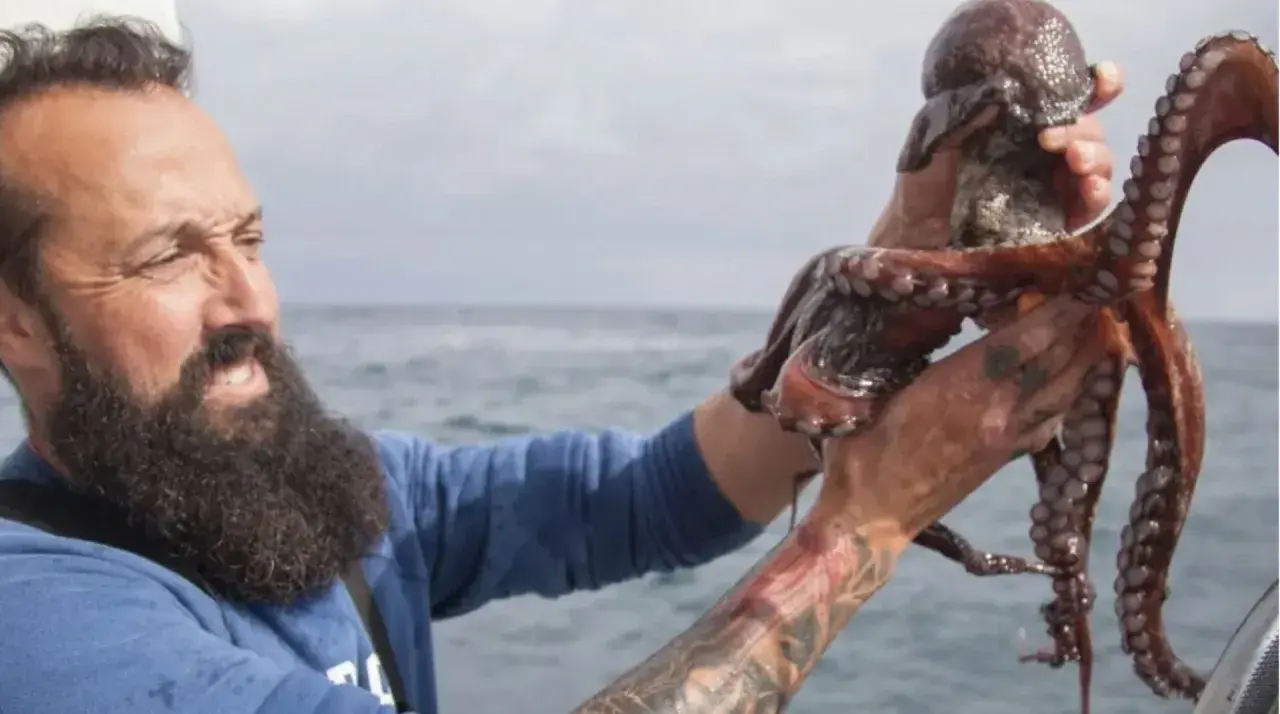 Pescador con pulpo recién capturado en el mar.