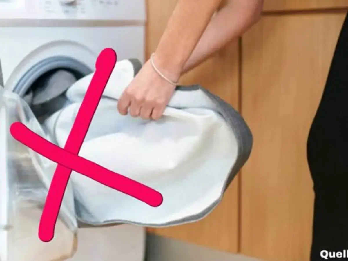 Rote Kreuze über einem weißen Wäschestück, das aus einer Waschmaschine genommen wird. Das zeigt, was darf nicht in den trockner.