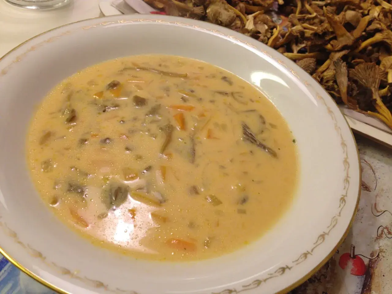 Krämig trattkantarellsoppa, perfekt för ett mysigt trattkantarellsoppa recept. Serveras i en elegant skål med torkad svamp i bakgrunden.