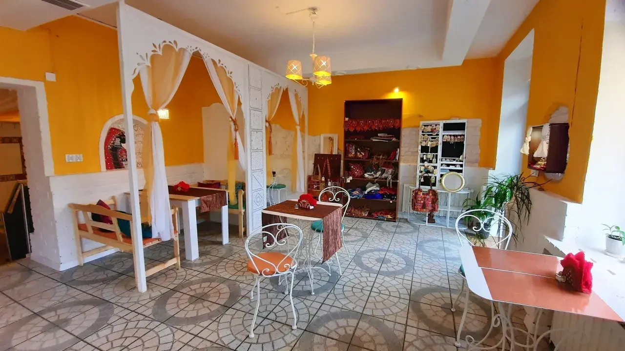 Wnętrze restauracji Samsara w Opolu, z żółtymi ścianami, białymi zdobieniami i stolikami. Idealne miejsce, by zapoznać się z ich menu.