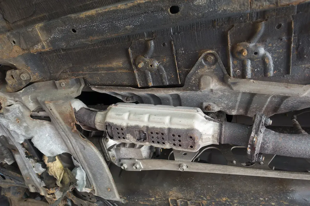 Vue du dessous d'une voiture montrant un catalyseur rouillé, nécessitant un nettoyage catalyseur pour améliorer les performances.