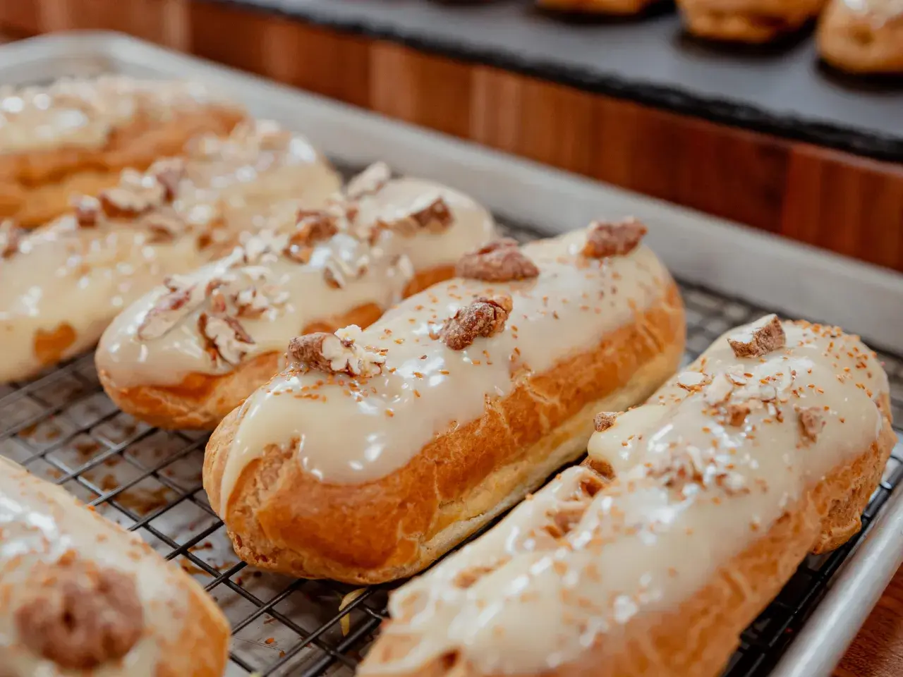 Éclairs dorés sur une grille, nappés d'un glacage sirop d'érable et parsemés de noix concassées. Un délice gourmand.