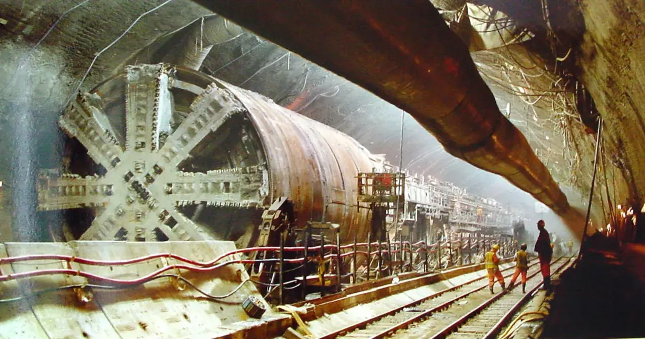 Ogromna tarcza drążąca tunel, budowa eurotunelu. Pracownicy nadzorują postęp prac w podziemnym korytarzu.