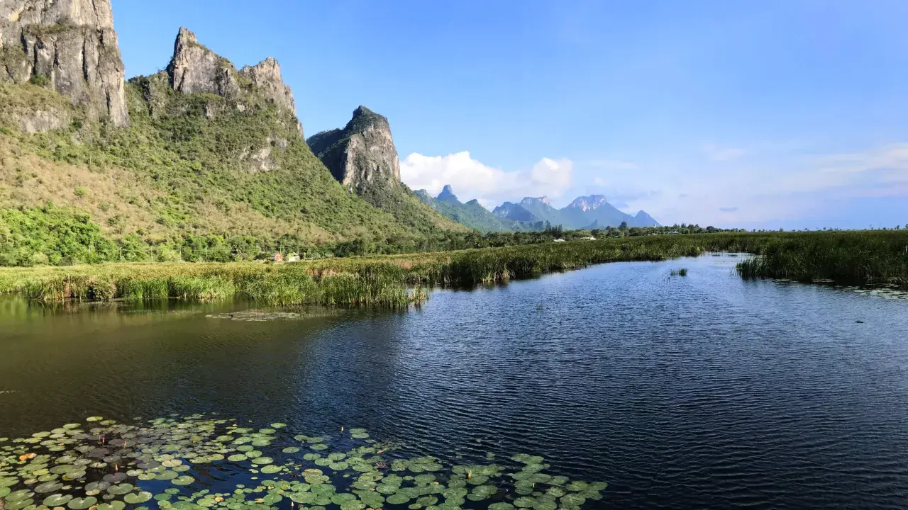 Khao Sam Roi Yot National Park: Majestätische Berge ragen über einen ruhigen Fluss mit Seerosen und Schilf auf.