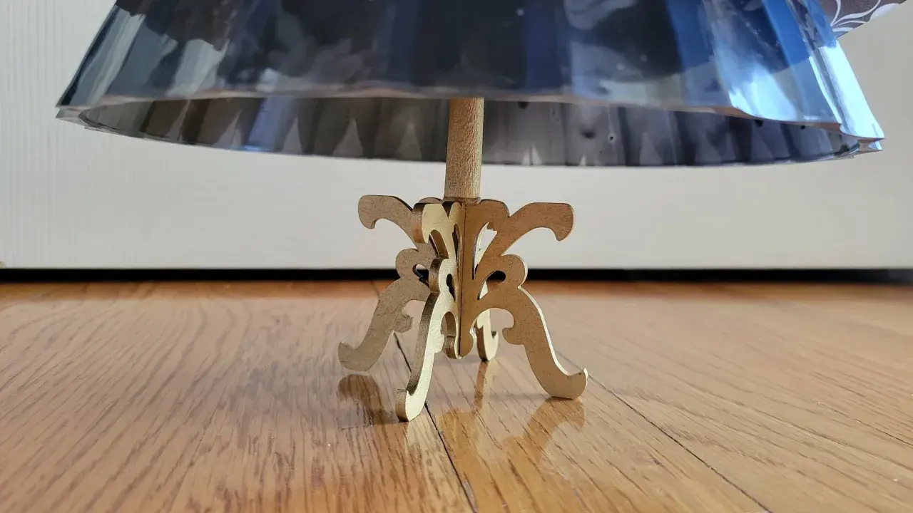 Base de un maniquí 3d de madera con un soporte ornamental, sosteniendo una falda de tela brillante.