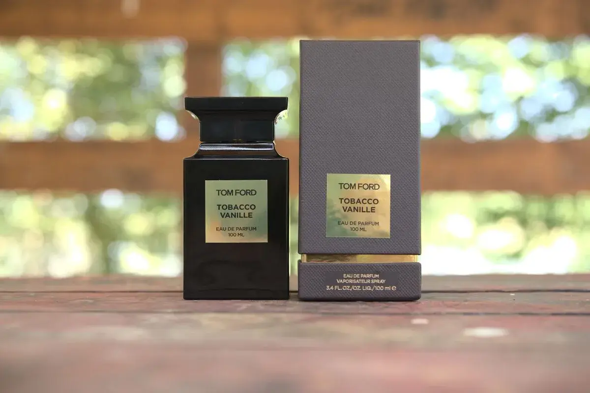 Elegancka butelka i pudełko perfum Tom Ford Tobacco Vanille na drewnianym tle.