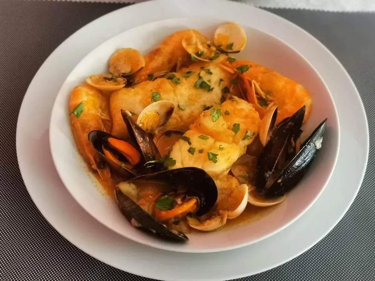 Caldereta de pescado con gambas, mejillones y almejas, todo ello espolvoreado con perejil fresco.